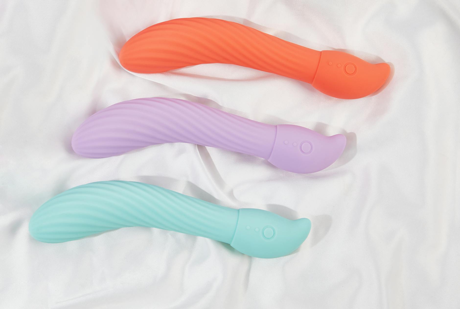 A stylish teal vibrator on smooth white silk fabric, representing intimate self-care and pleasure