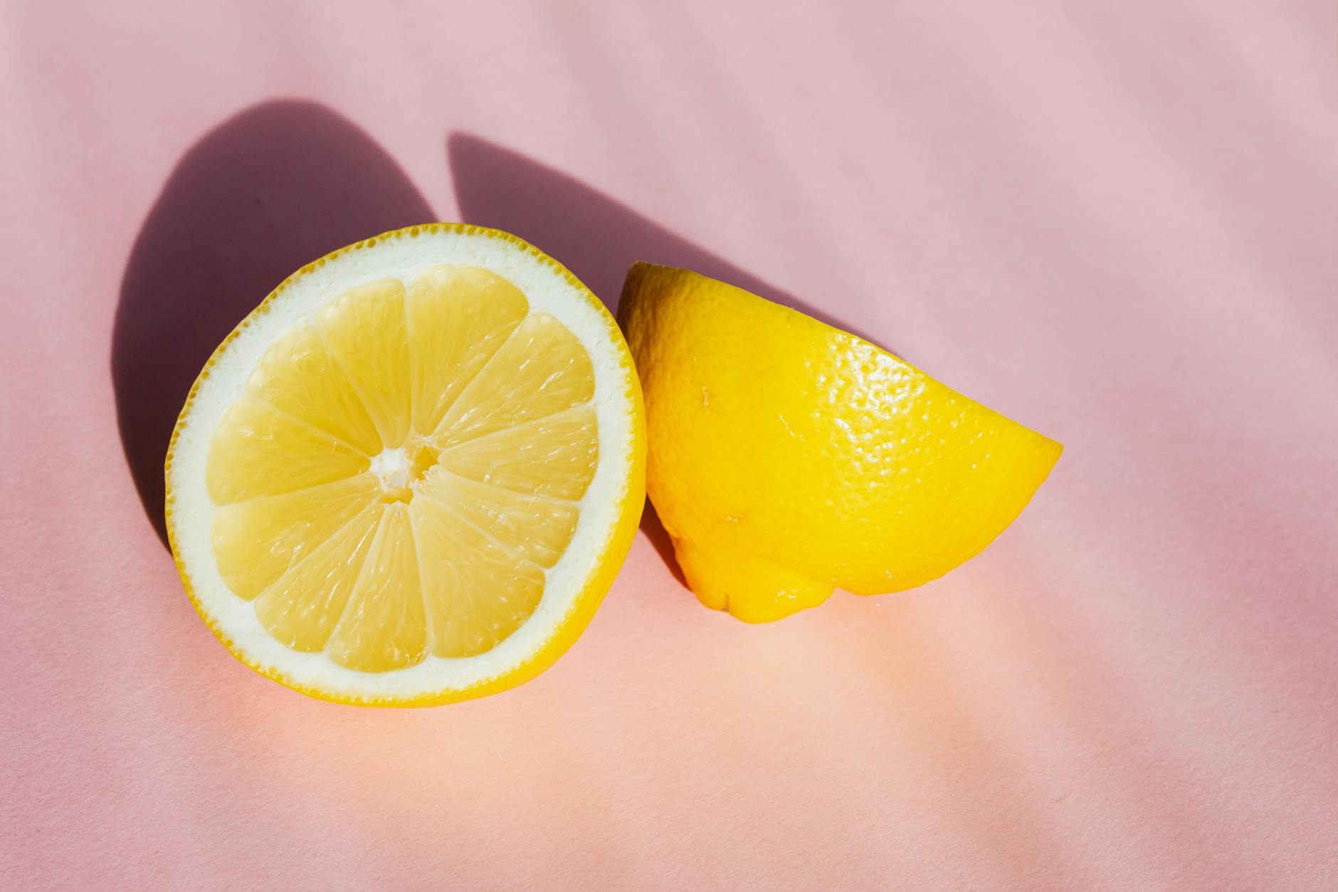 Fresh lemon halves on a pink background with warm sunlight