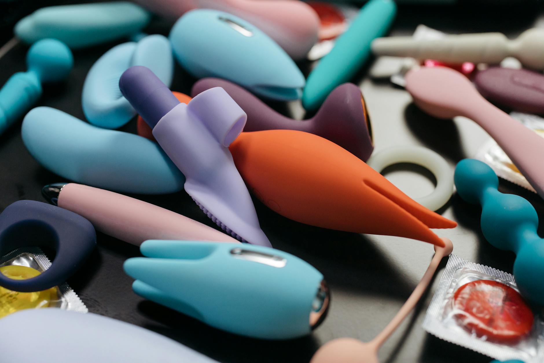 A teal lemon clitoral vibrator resting on smooth white silk fabric