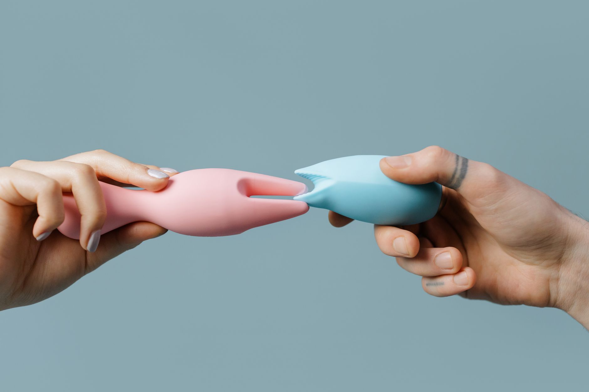 Hands holding colorful silicone vibrators and intimate wellness toys