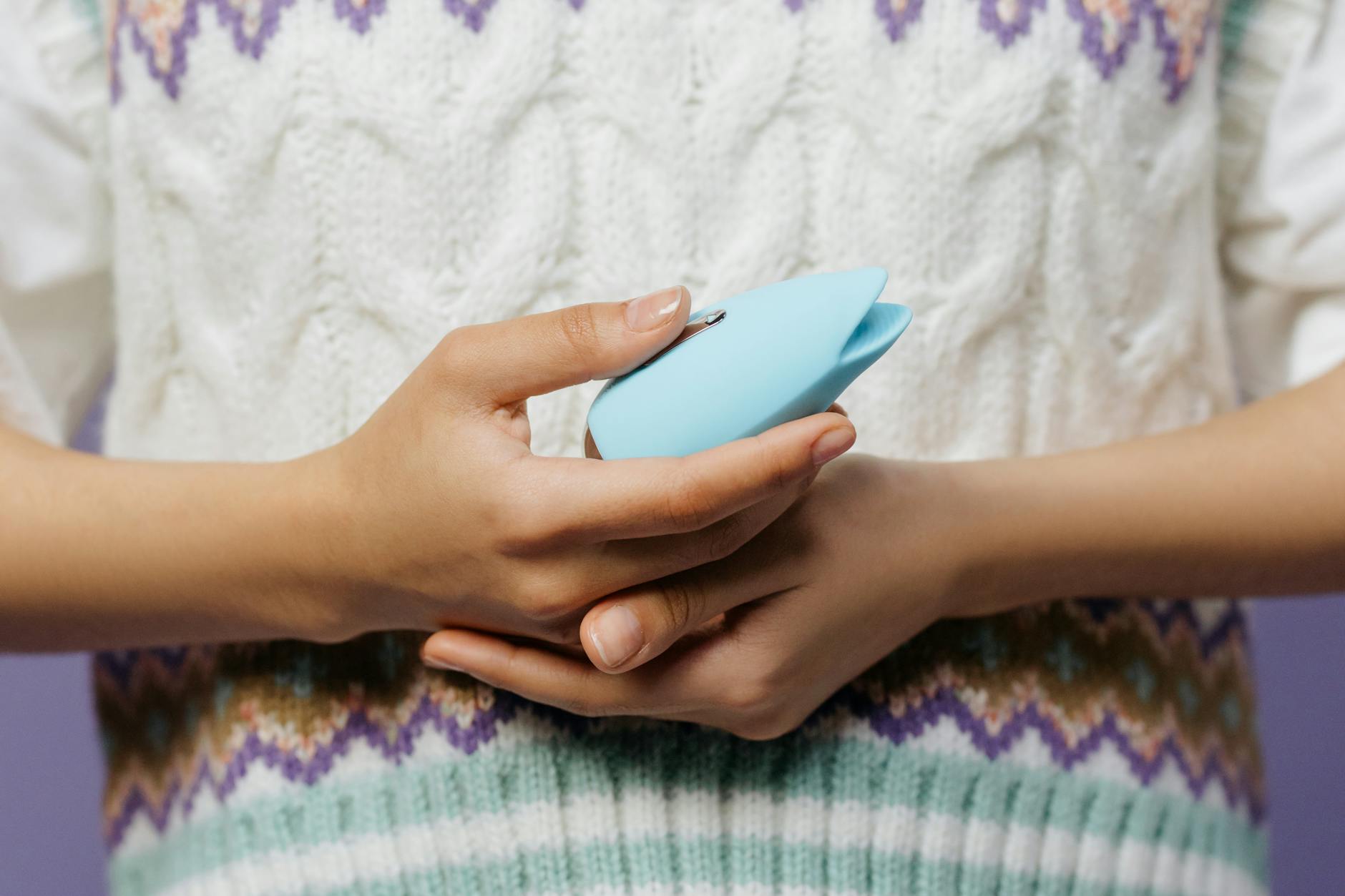 Close-up of hands holding a lemon vibrator against a knitted sweater