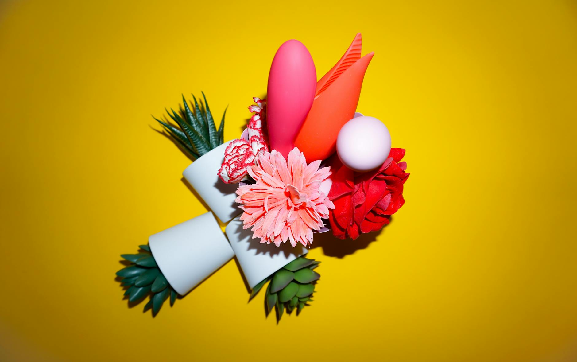 Studio display of colorful silicone sex toys on bright yellow background